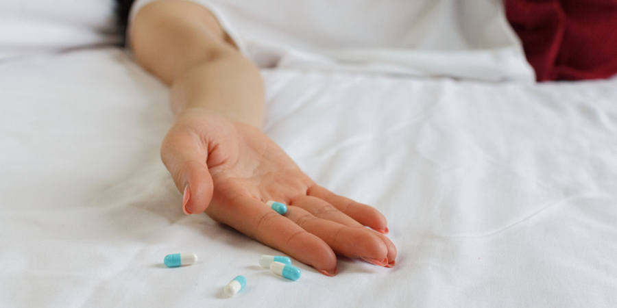 hand with pills in a hospital bed